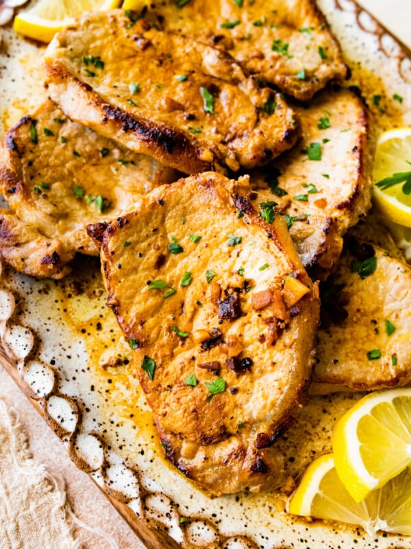 close up of the thin pork chops on a serving platter with lemon wedge.