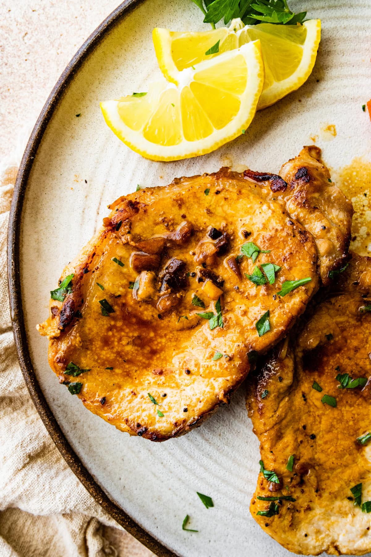 two juicy thin pork chops on a plate wit cooked carrots as a side dish.