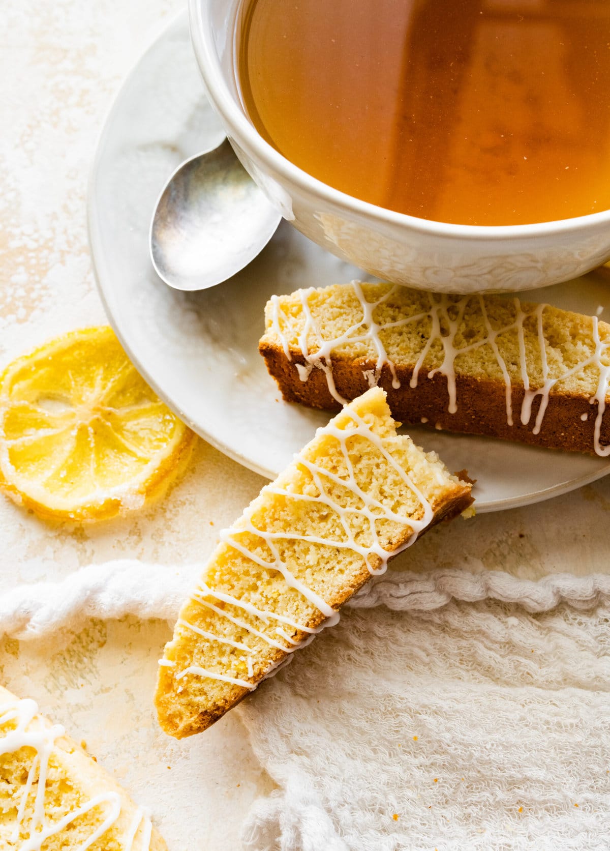 beautiful lemon biscotti on white background with lemon slices around it and tea.