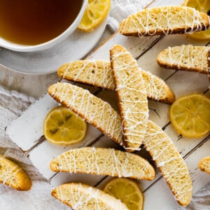 Lemon biscotti stacked on a plate at different directions with lemon slices.