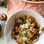 butternut squash casserole in a serving bowl with herbs.