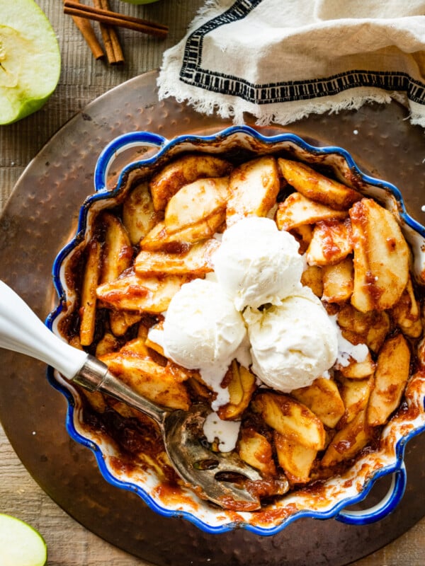 Easy baked cinnamon apples in a pie plate with blue rim. Vanilla Ice cream in the middle of apples.