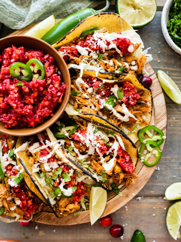 Leftover turkey tacos on a tray with a bowl of cranberry relish.