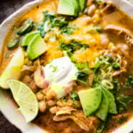 Bowl of white chicken chili topped with sour cream, avocado, cheese, and lime.