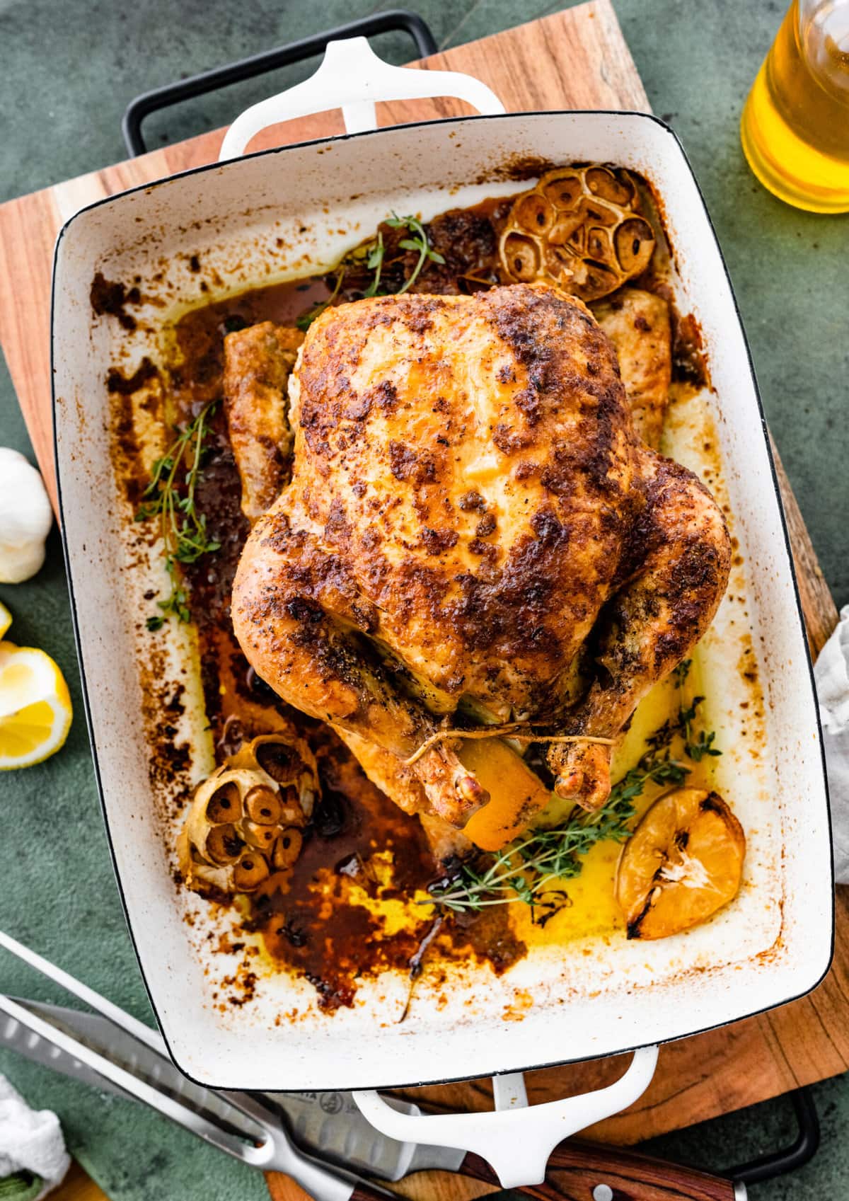 How Long to Cook Whole Chicken Recipe Perfect & Juicy- cooked roast chicken in a large roasting pan with lemons and garlic on the side.