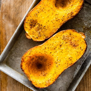 Roasted, halved butternut squash on a baking sheet.