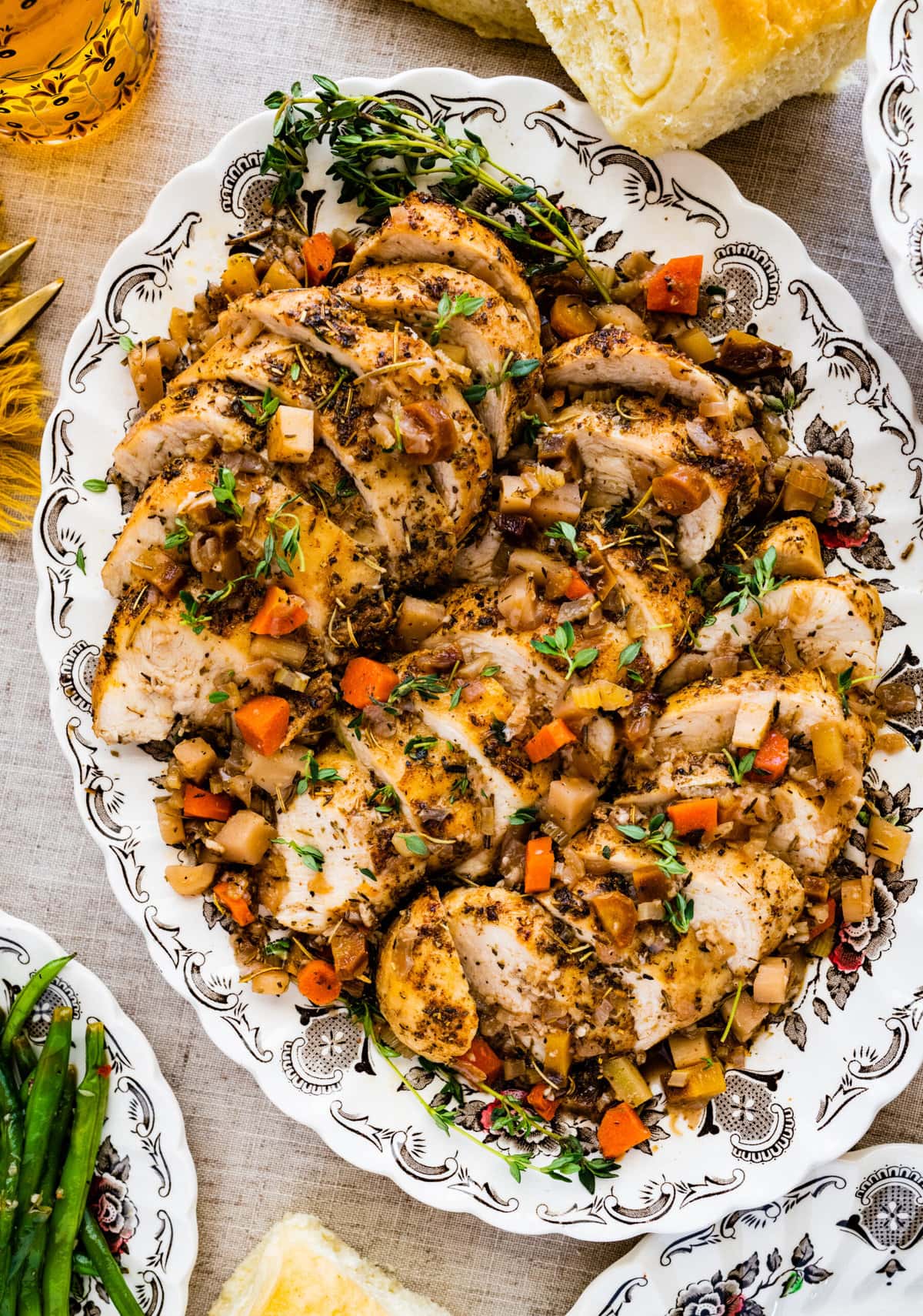 Beautiful sliced Juicy Oven Baked Chicken Breast Recipe on a serving platter with cooked veggies on top.