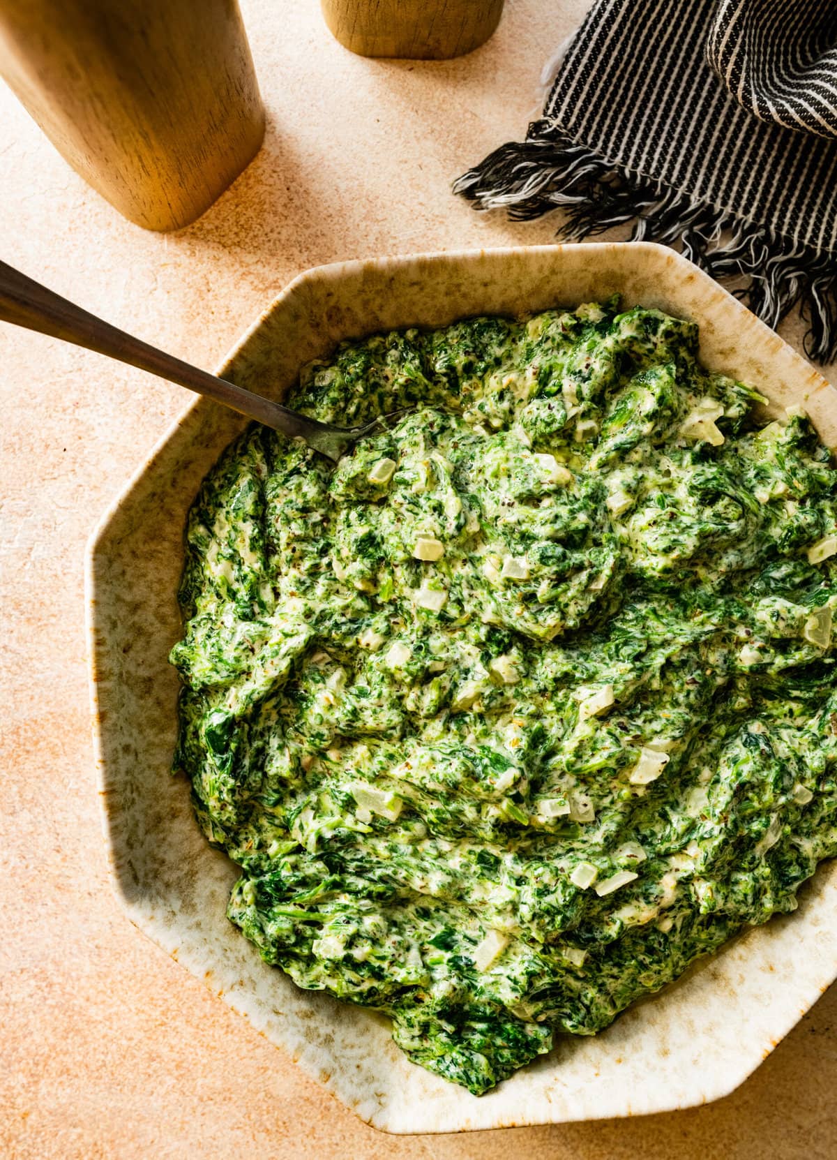 scooping up best steakhouse creamed spinach recipe with a spoon in it.