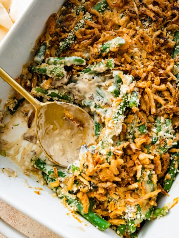 fresh green bean casserole in a baking dish with serving spoon in it.