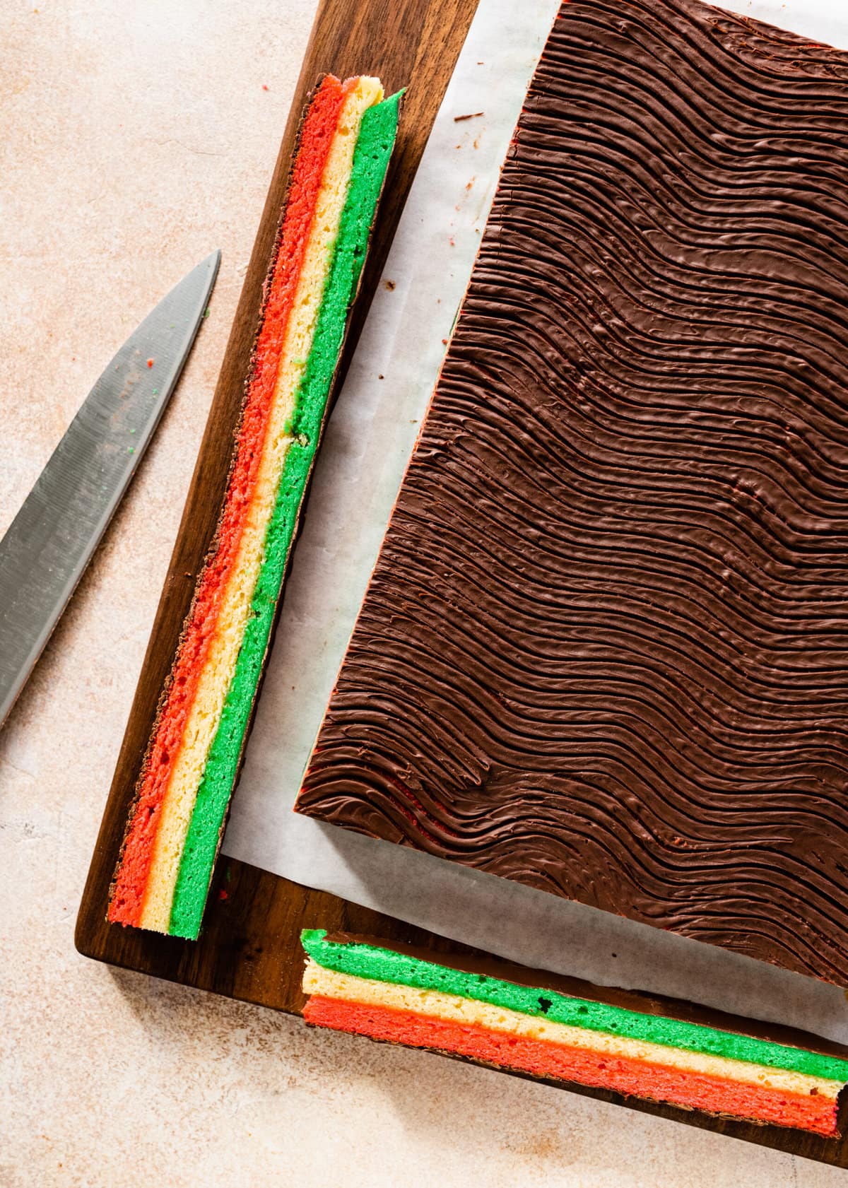 How to make Calssic Italian Rainbow Cookies Step-by-Step Instructions: making a swirl pattern on top of the top of cake layer with a fork. Cutting off the edges for a clean cut.