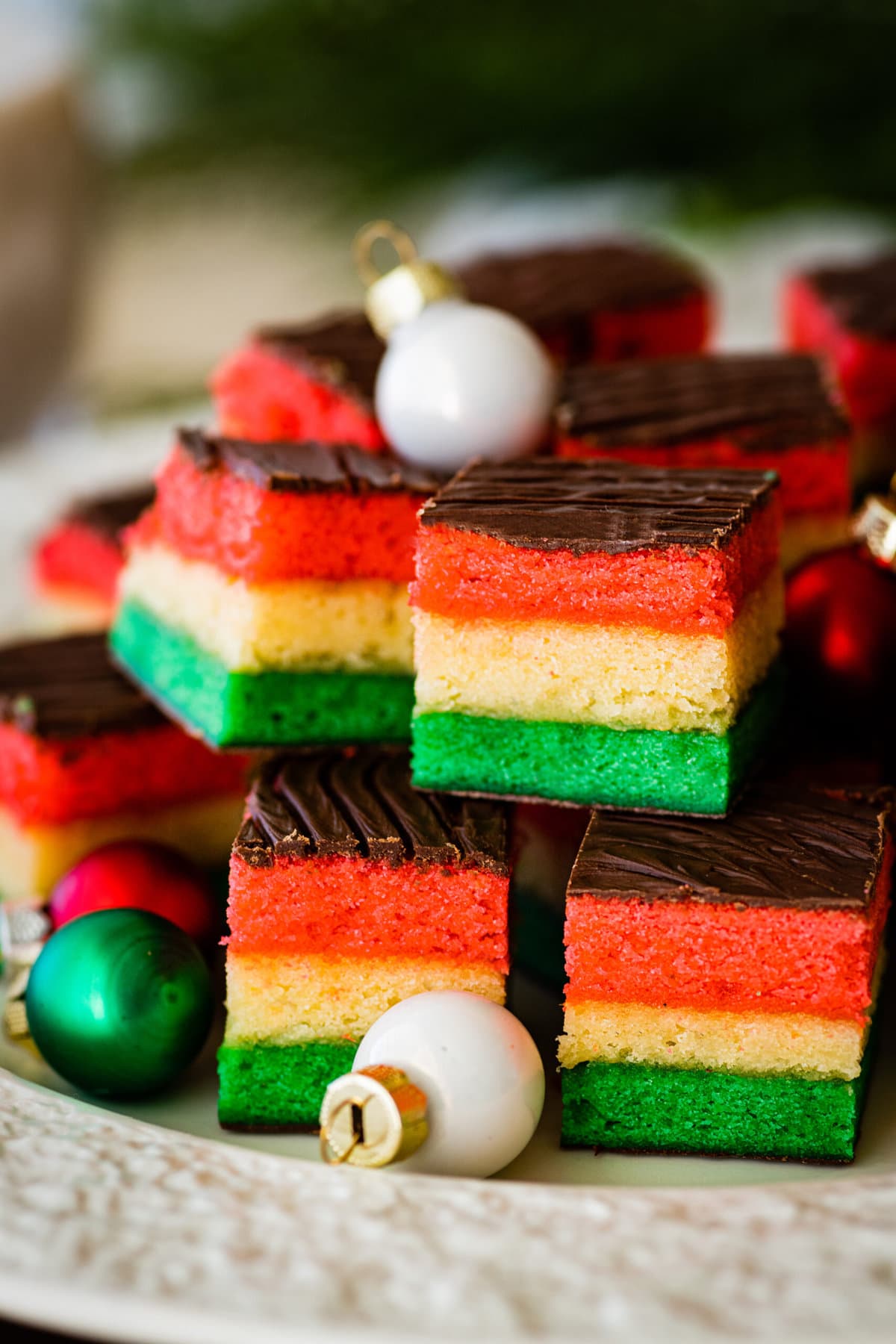 Classic Italian Rainbow Cookies Recipe- with tiny red, white, and green Christmas ornaments. 