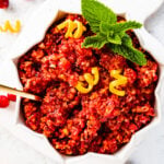 Spoon in fresh cranberry relish in a white bowl with several points.