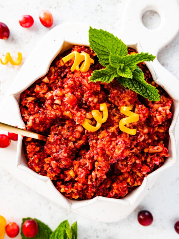 Spoon in fresh cranberry relish in a white bowl with several points.