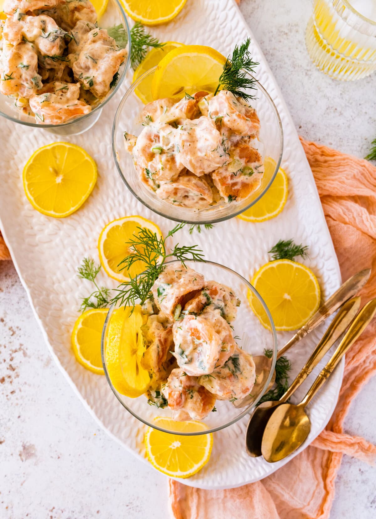 easy shrimp salad recipe in a small clear serving class with lemon and dill as decoration.