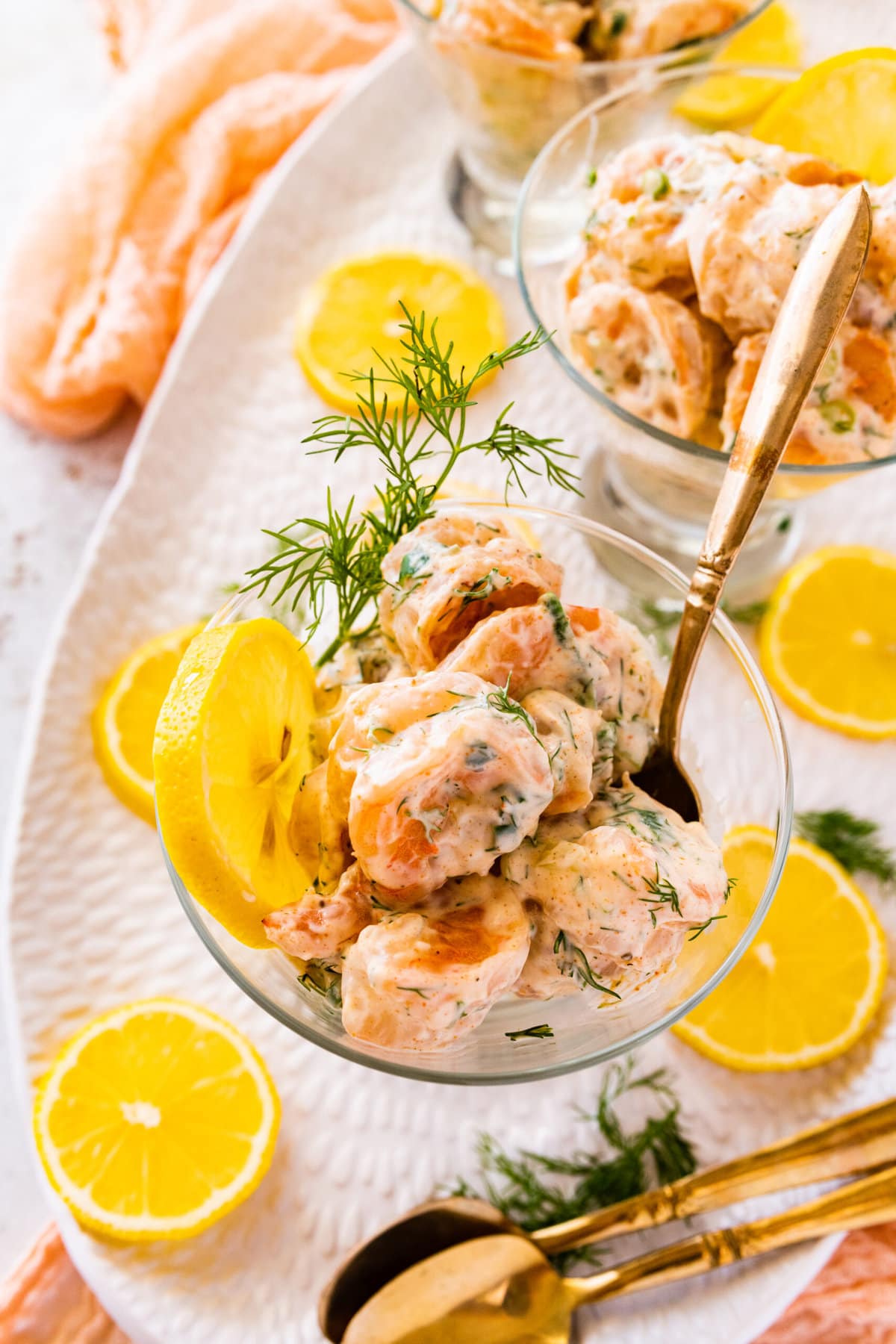 easy shrimp salad recipe in a small clear serving class with lemon and dill as decoration.