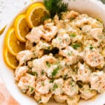 how to make shrimp salad step-by-step: shrimp salad in serving bowl with fresh lemons and dill to decorate.