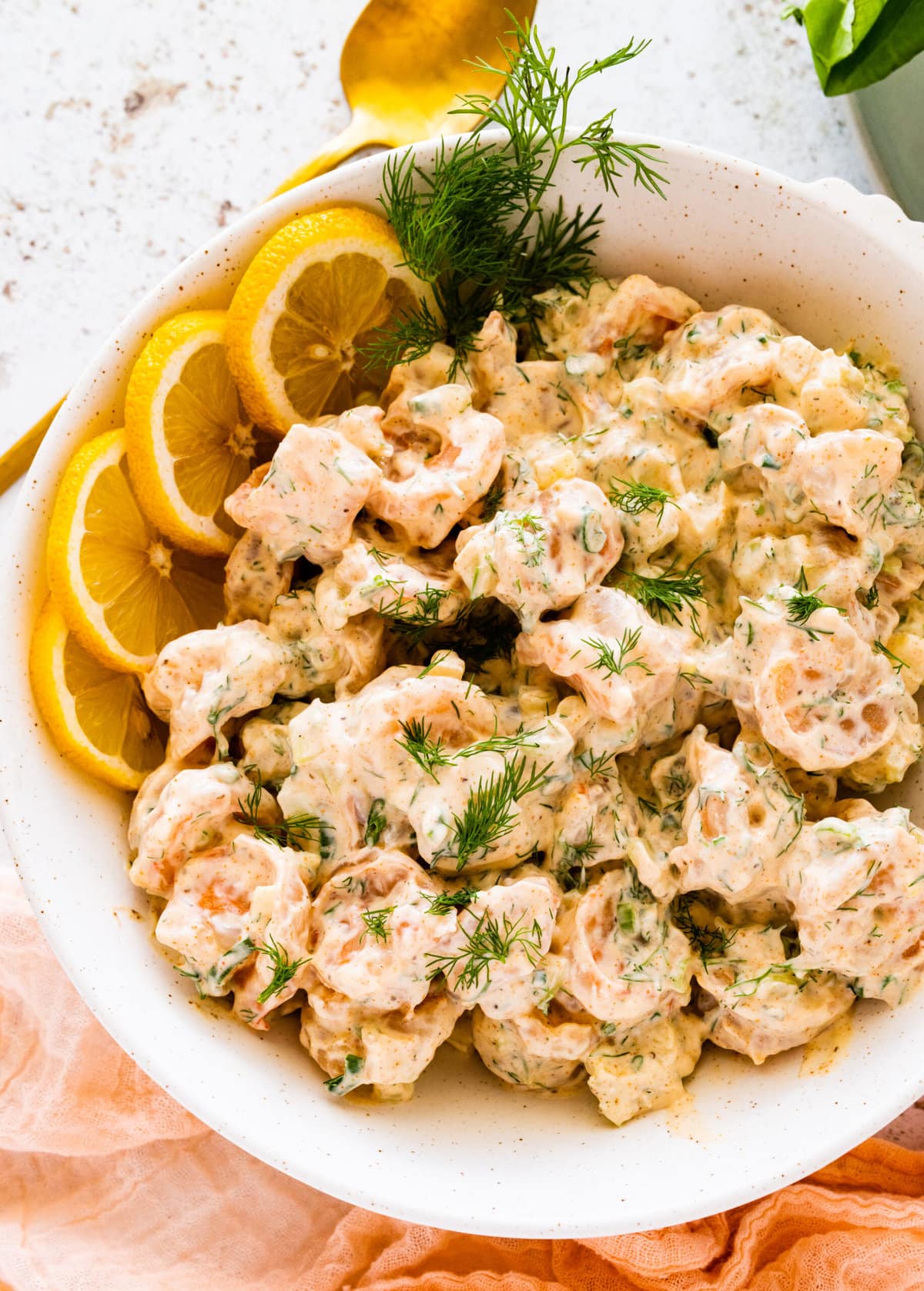 how to make shrimp salad step-by-step: shrimp salad in serving bowl with fresh lemons and dill to decorate. 