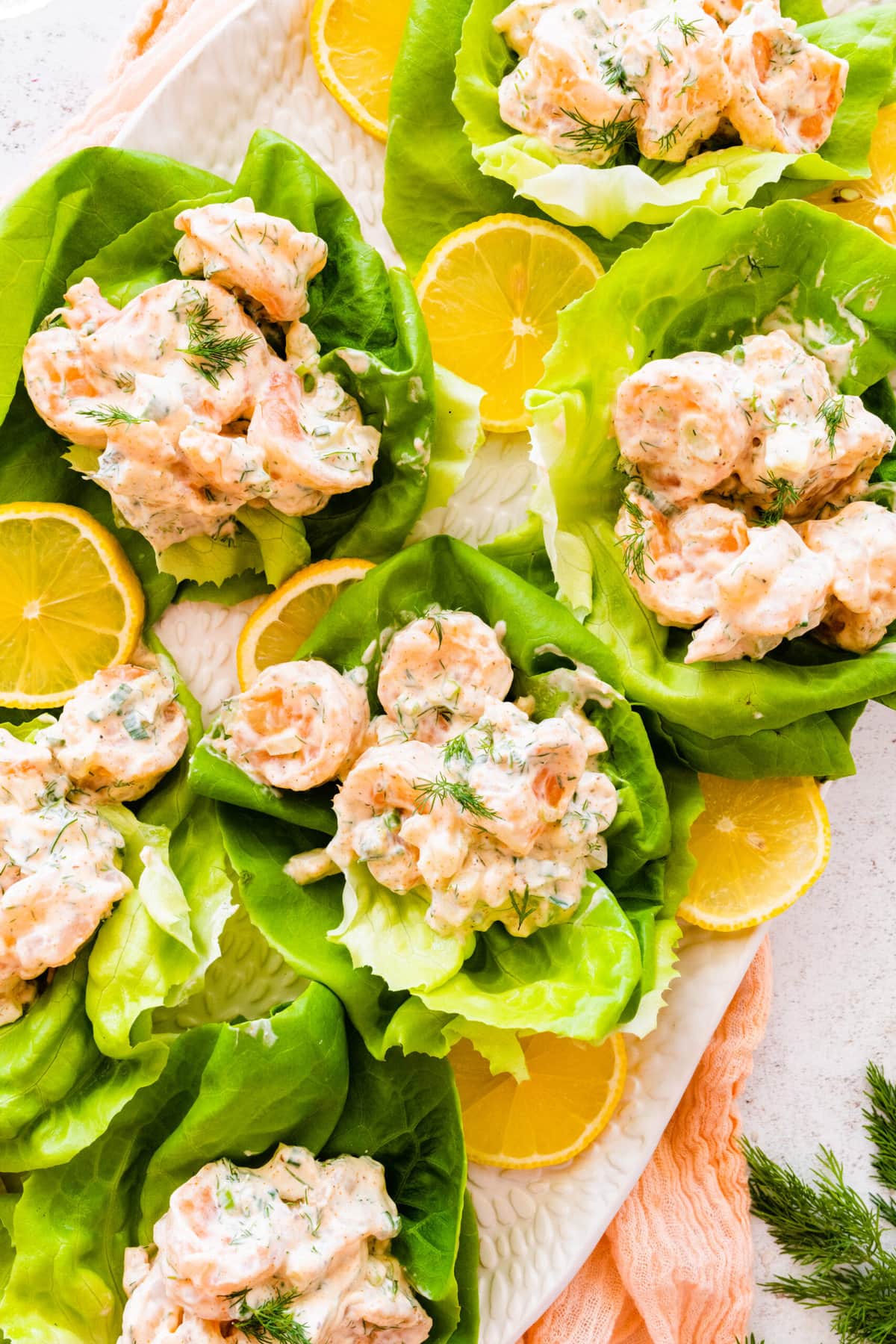 close up- of the shrimp salad with old bay seasoning in lettuce cups on a pretty platter. Lemons on the side.