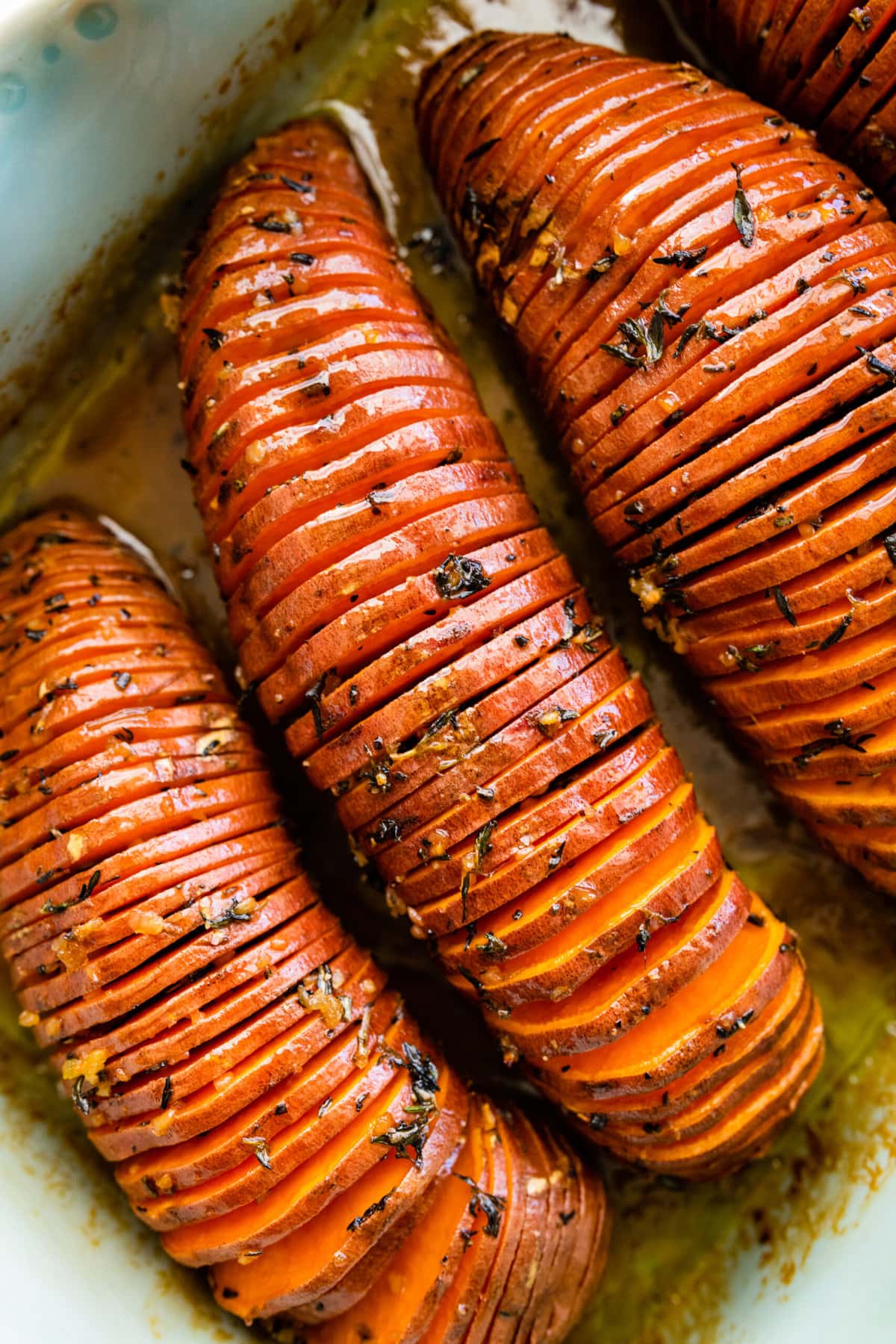 How to make Hasselback Sweet Potatoes with Maple Syrup: potatoes after they are done baking in a teal baking dish.