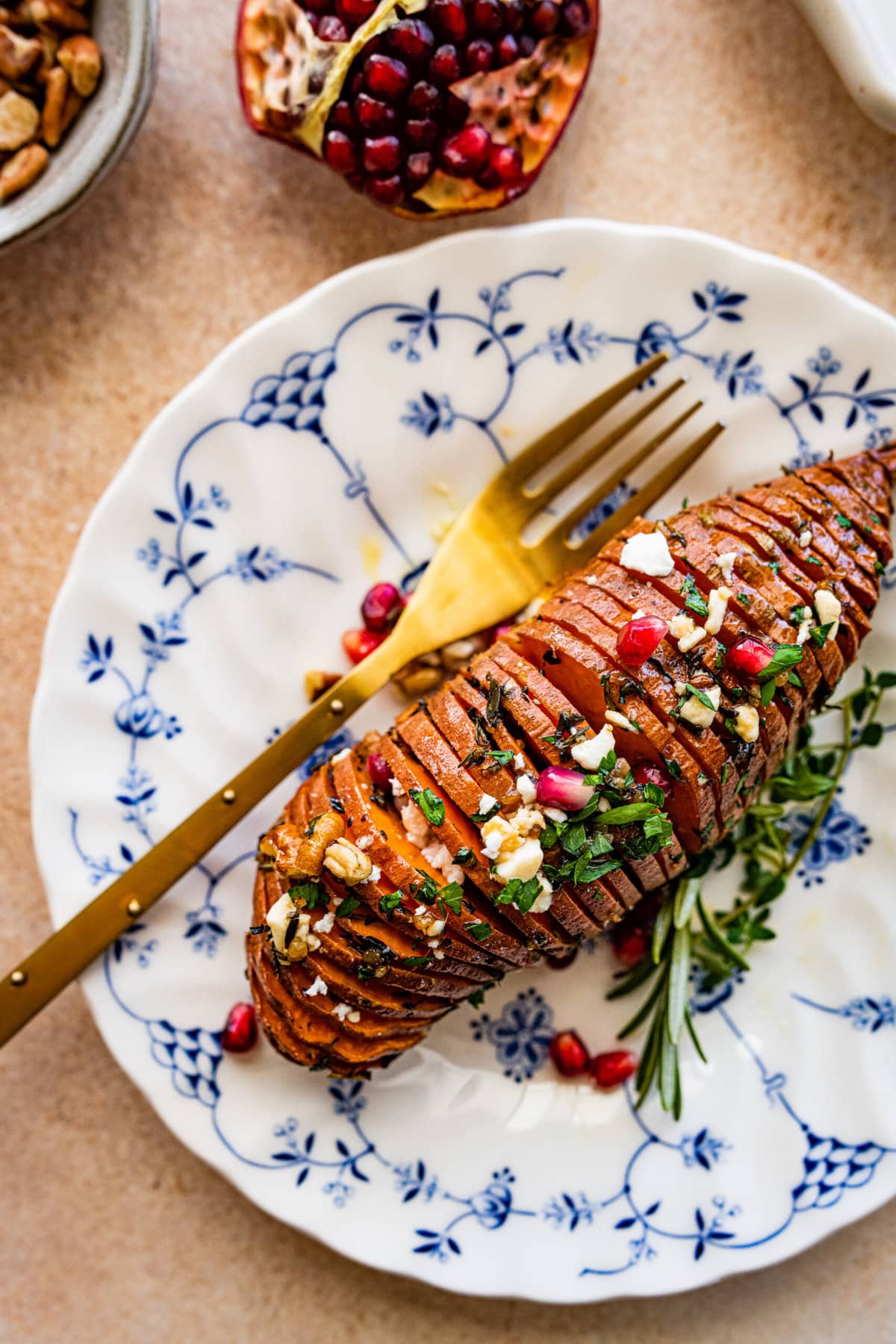 hasselback sweet potato on a plate with a fork. The plate has a pretty blue design.