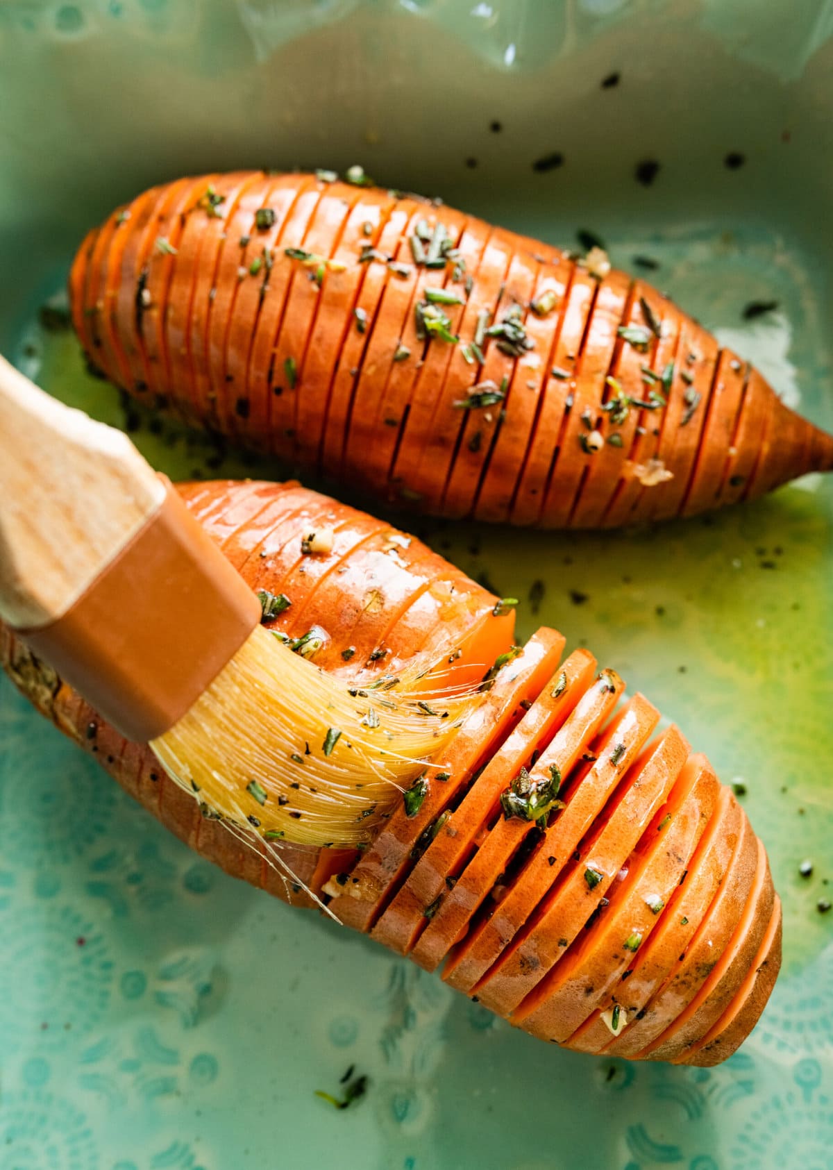 How to make Hasselback Sweet Potatoes with Maple Syrup: brushing the oil and herb seasoning.