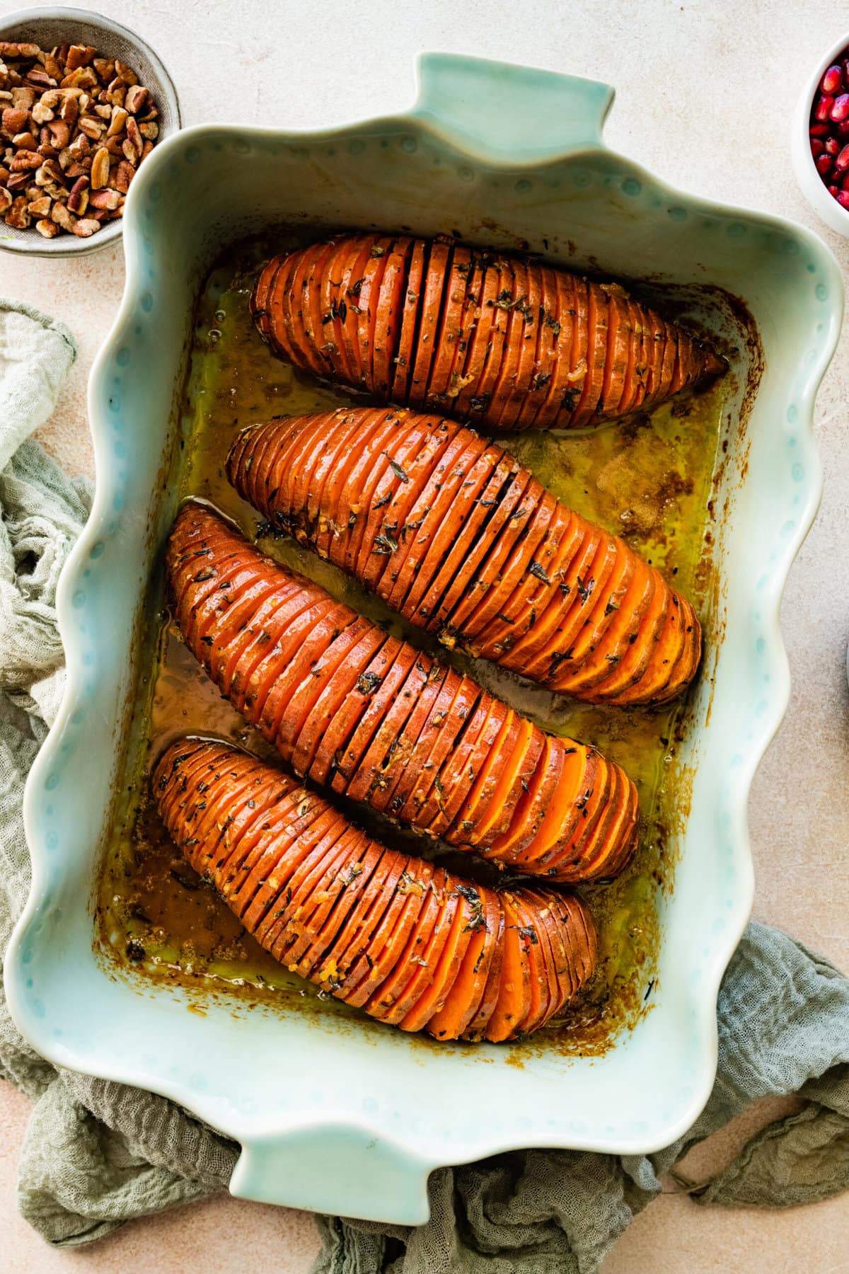 How to make Hasselback Sweet Potatoes with Maple Syrup: potatoes after they are done baking in a teal baking dish.