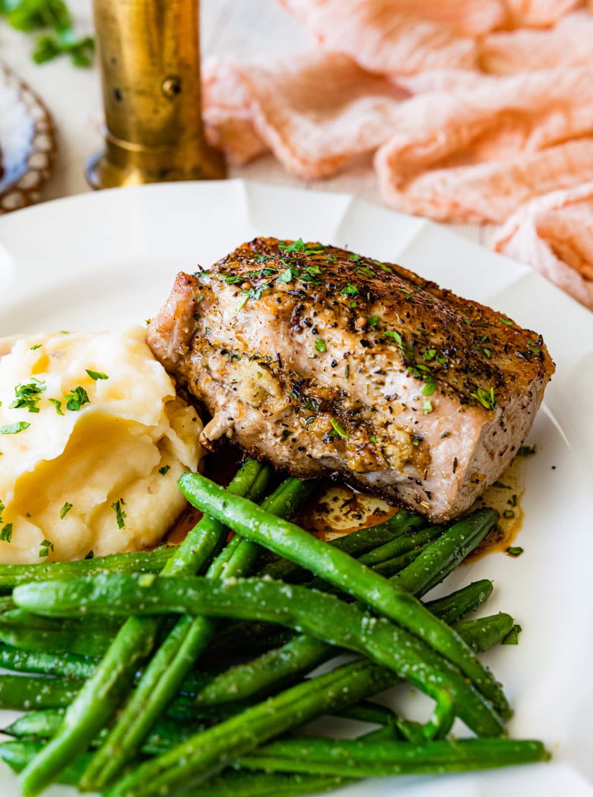oven baked stuffed pork chop on plate with green beans and mashed potatoes.