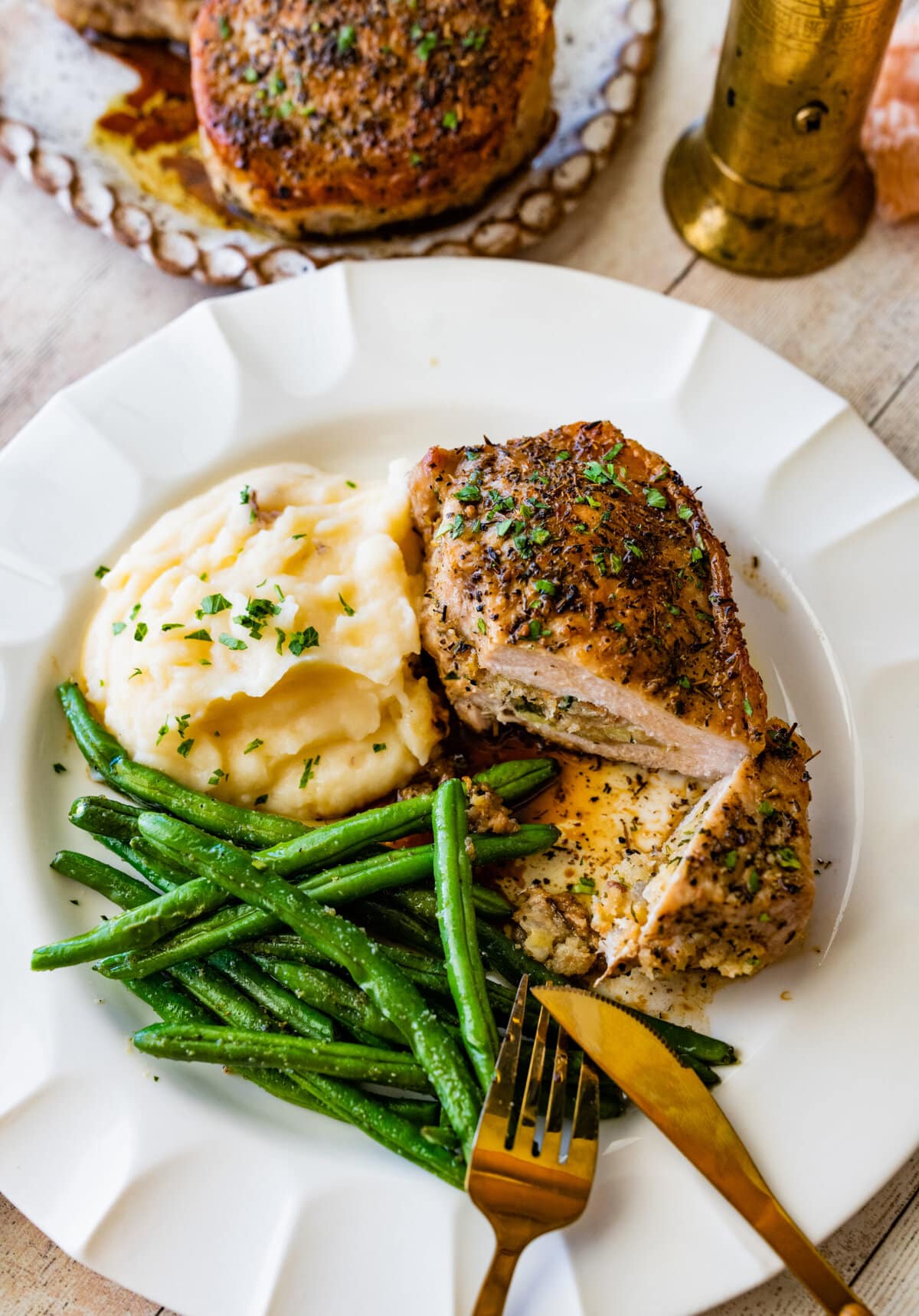 stuffed pork chop cut open to see filling with green beans and mashed potatoes.