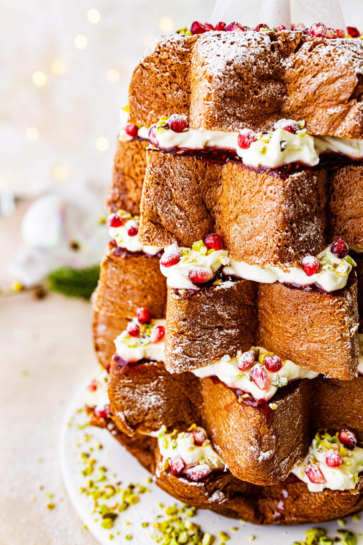 up close of layers of pandoro cake with cream and pomegranate and pistachios.