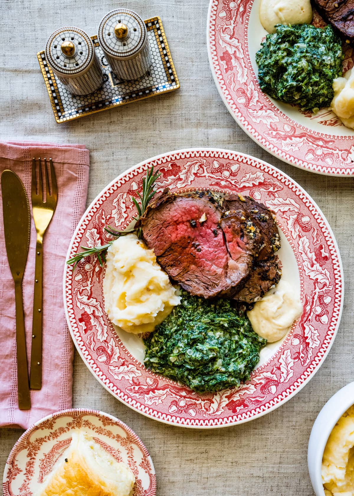 platted roast beef tenderloin with mashed potatoes and creamed spinach. A side of horseradish sauce. fork and knife on the side of the plate.