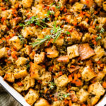 Vegetarian Stuffing Casserole Recipe in a white casserole dish with extra herbs on top.