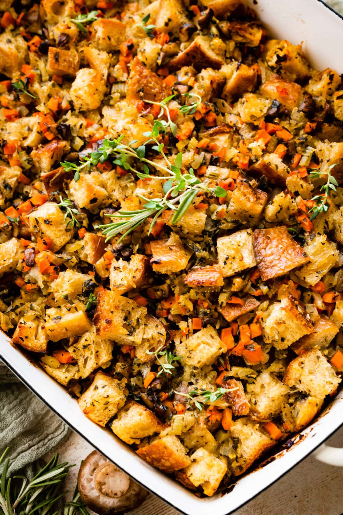 Vegetarian Stuffing Casserole Recipe in a white casserole dish with extra herbs on top.