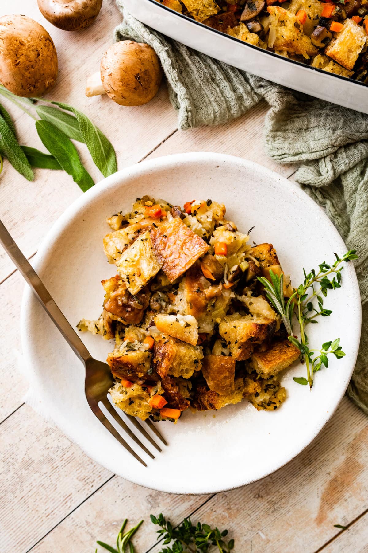 a portion of veg stuffing on a white plate with a fork. Herbs around the plate.