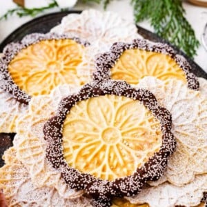 Best pizzelle cookies recipe with dip of chocolate around the edges and tiny white pearl sprinkles.