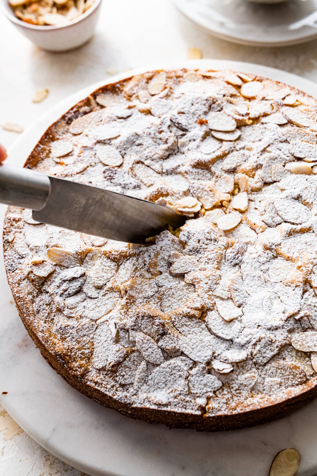 knife cutting into the almond cake recipe.