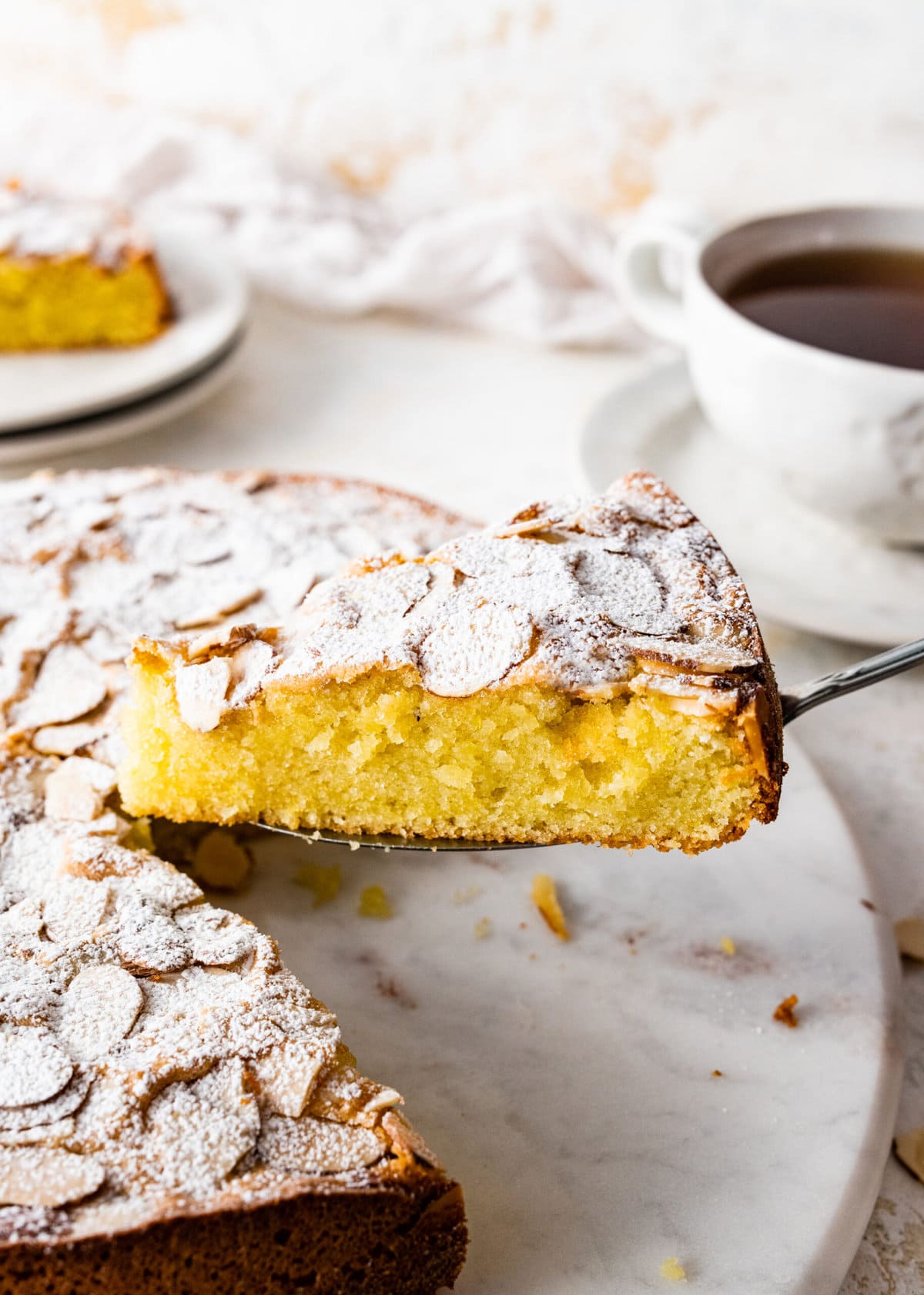 cake server holding up a slice of the almond cake.