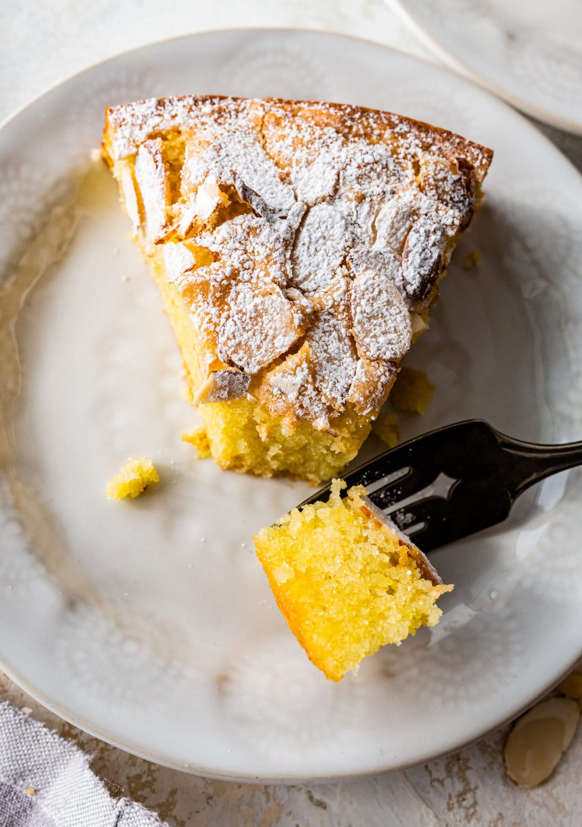 easy almond cake recipe on a plate with a fork taking a bite.