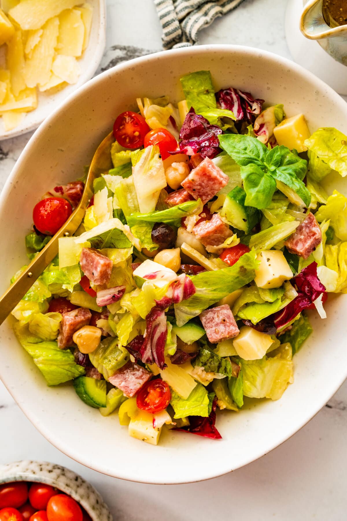 close up of bowl with salad ready to eat with extra cheese on the side.