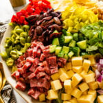 how to make Italian chopped salad step-by-step: adding all of the ingredients to the top of the salad.