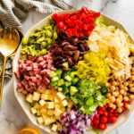 Italian chopped salad with all of the ingredients on top of the lettuce in sections to show all the colors and flavors.