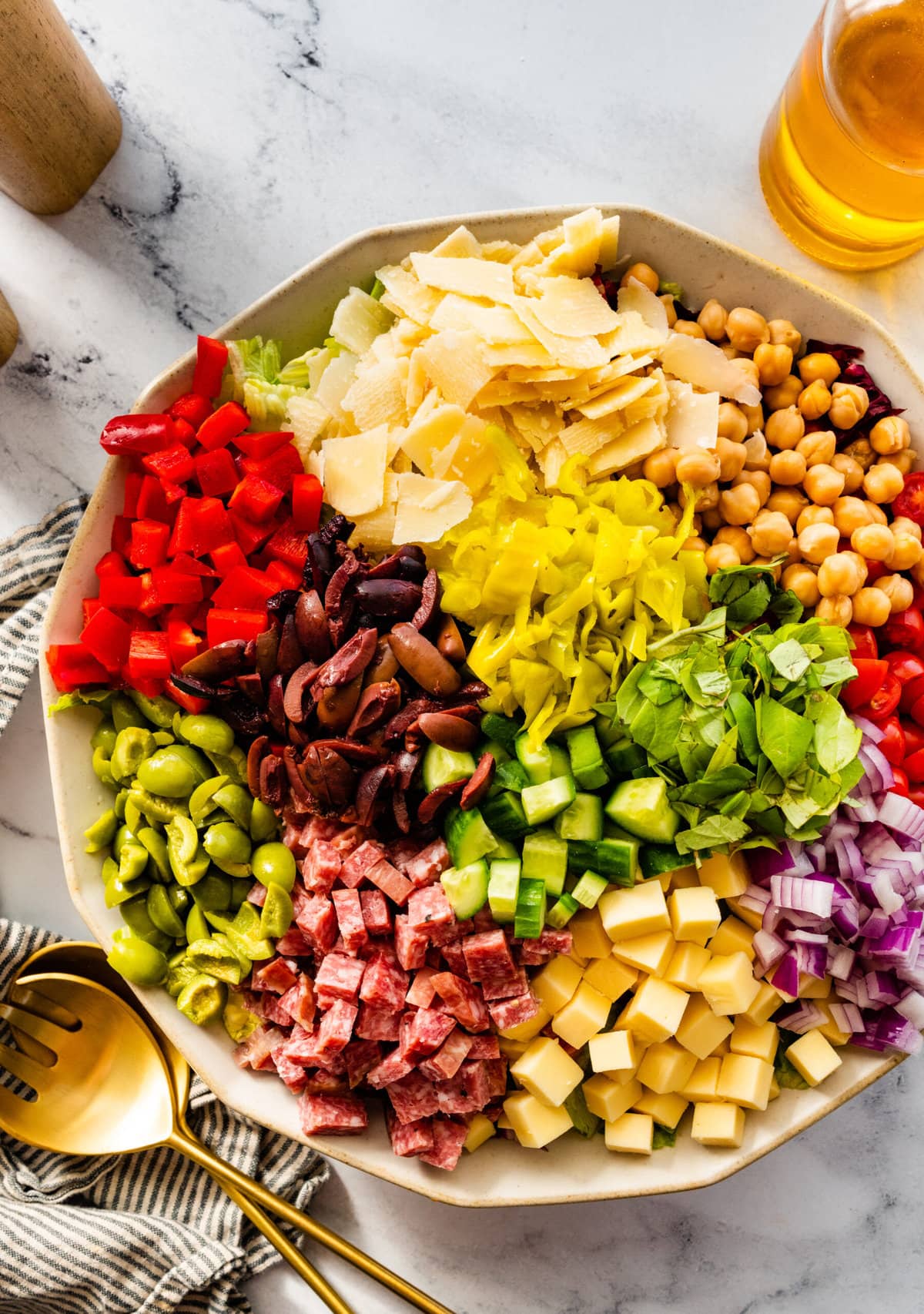 Italian chopped salad with all of the ingredients on top of the lettuce in sections to show all the colors and flavors.