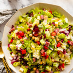 how to make Italian chopped salad step-by-step: mixing all of the ingredients together in a large salad bowl.