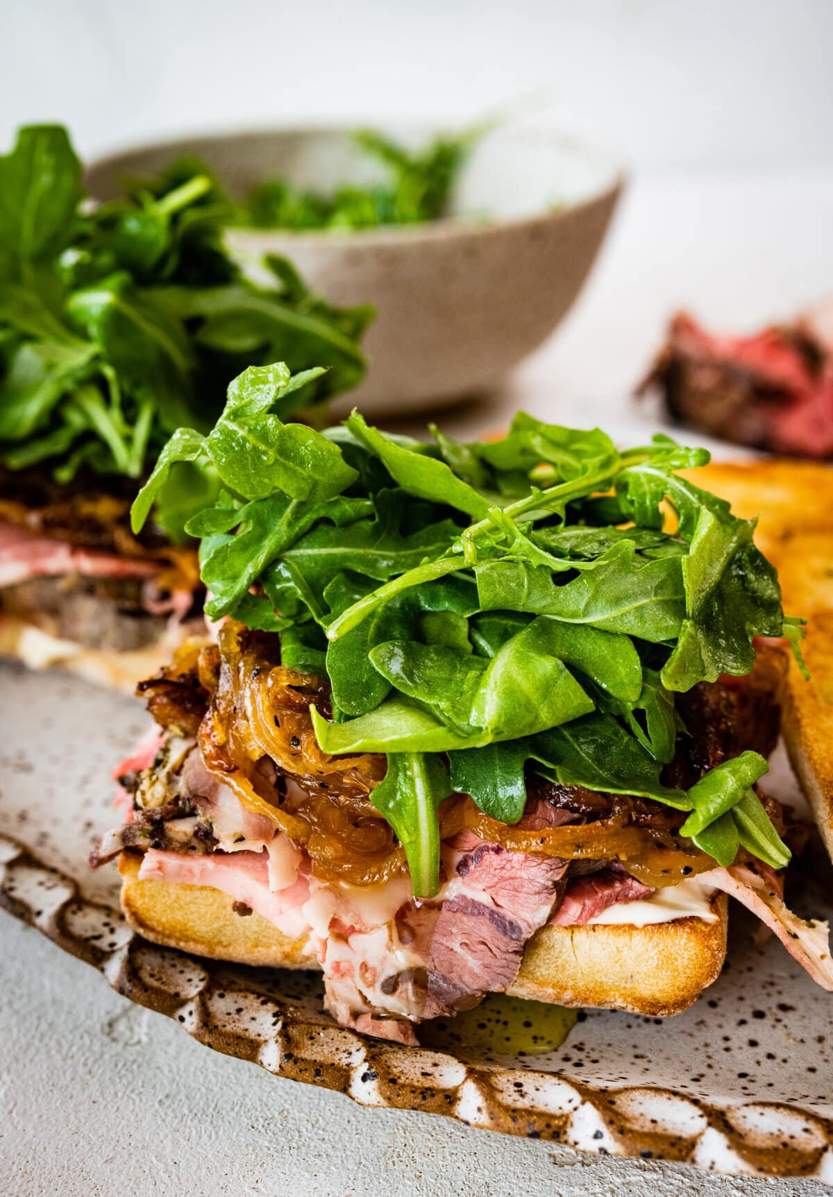 side view of the final prime rib sandwich with arugula on the top of it.