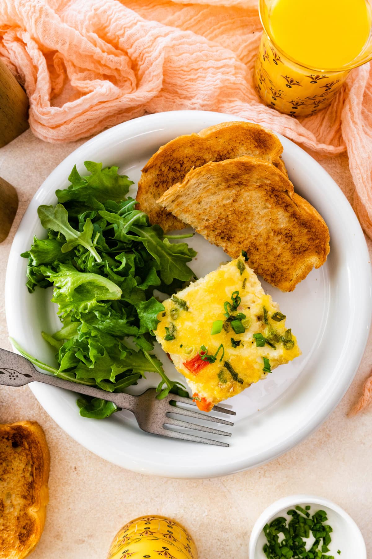 slice of breakfast casserole on a plate with toast and green salad.