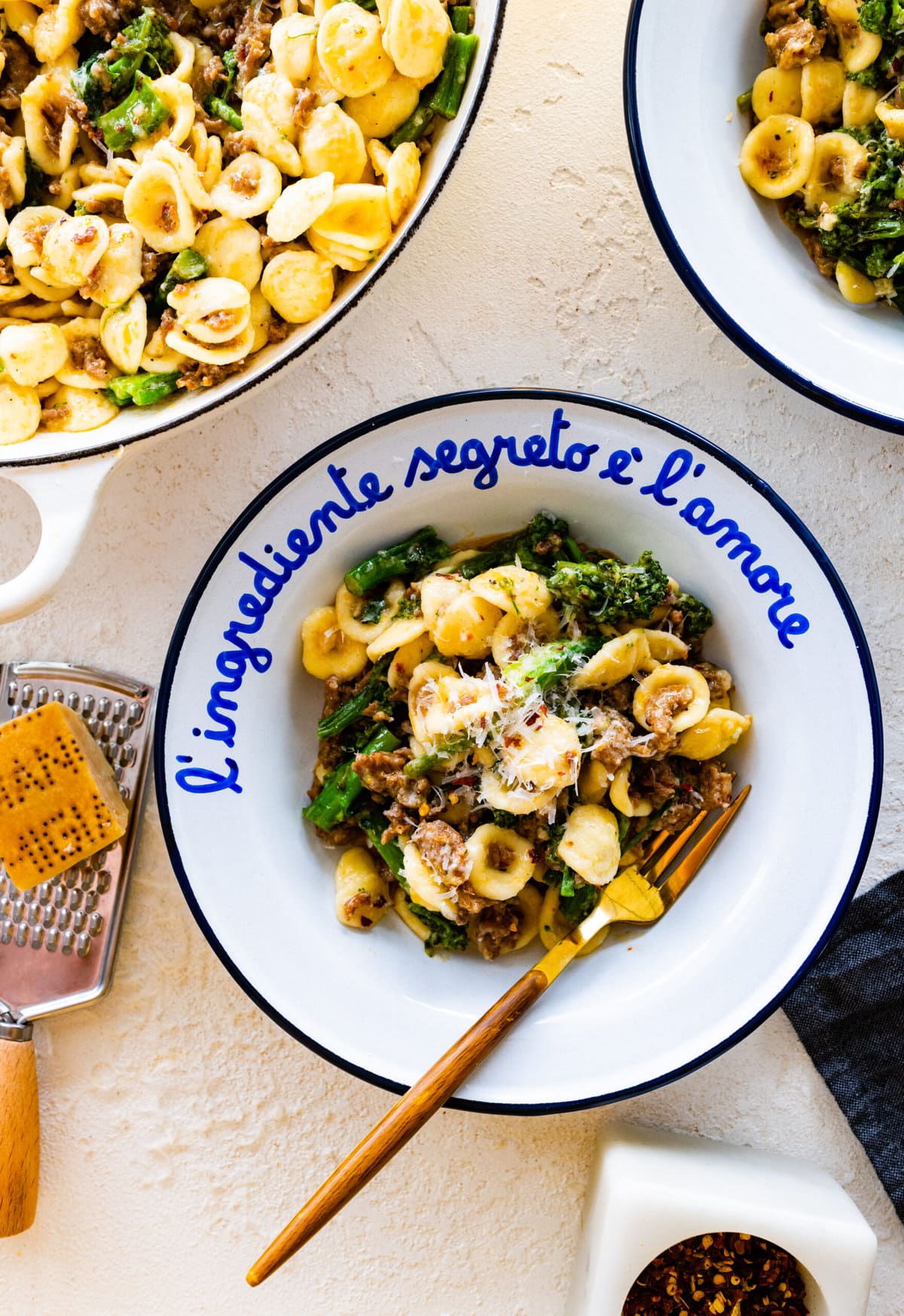 portion of orecchiette pasta dish in a white and blue Italian bowl. Extra parmigiano on top as garnish.