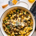 Orecchiette with sausage and broccoli topped with cheese in a Dutch oven.