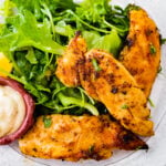chicken tenders on a plate with fresh green salad.
