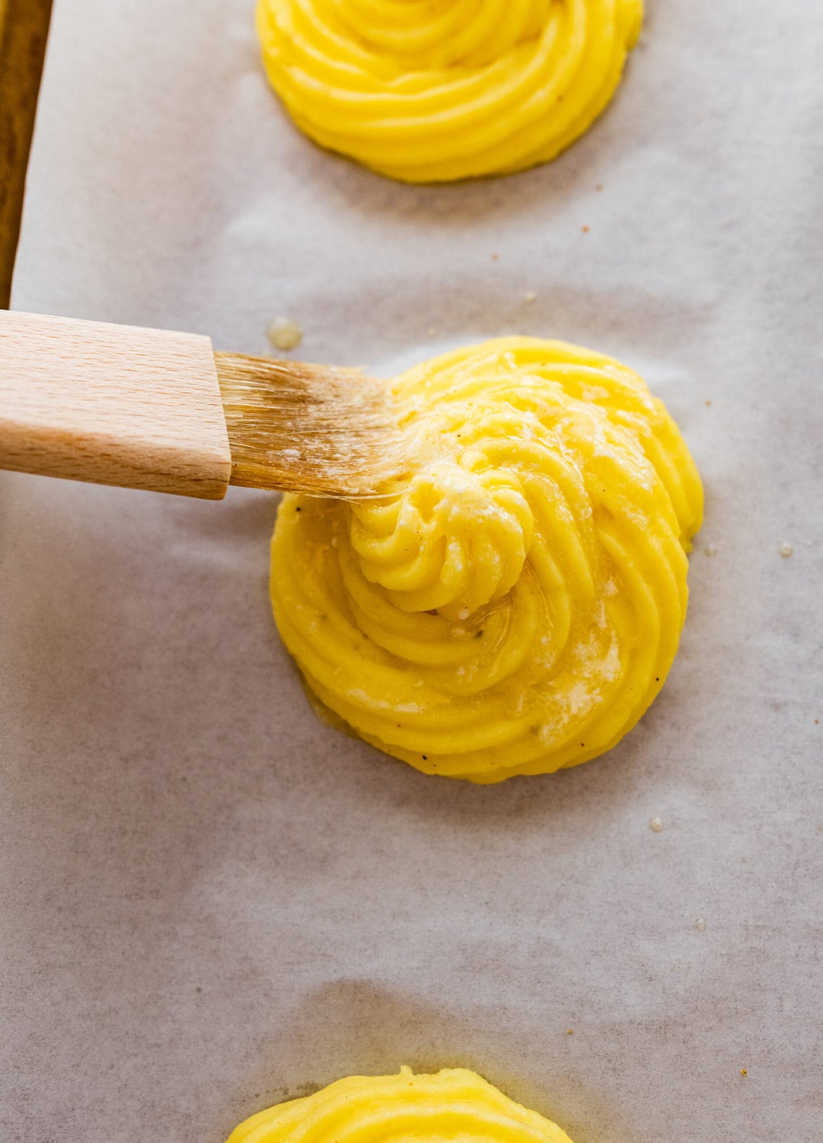 How to make duchess potatoes step-by-step: brush the duchess potatoes with butter.