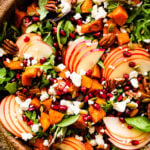 Bright harvest salad with apple and butternut squash topped with pomegranate seeds.