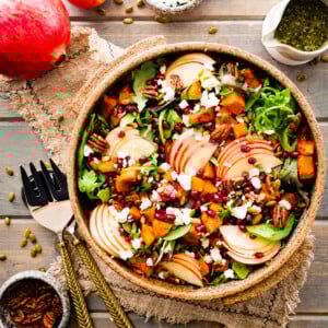 Bright fall harvest salad in a large bowl next to serving utensils.